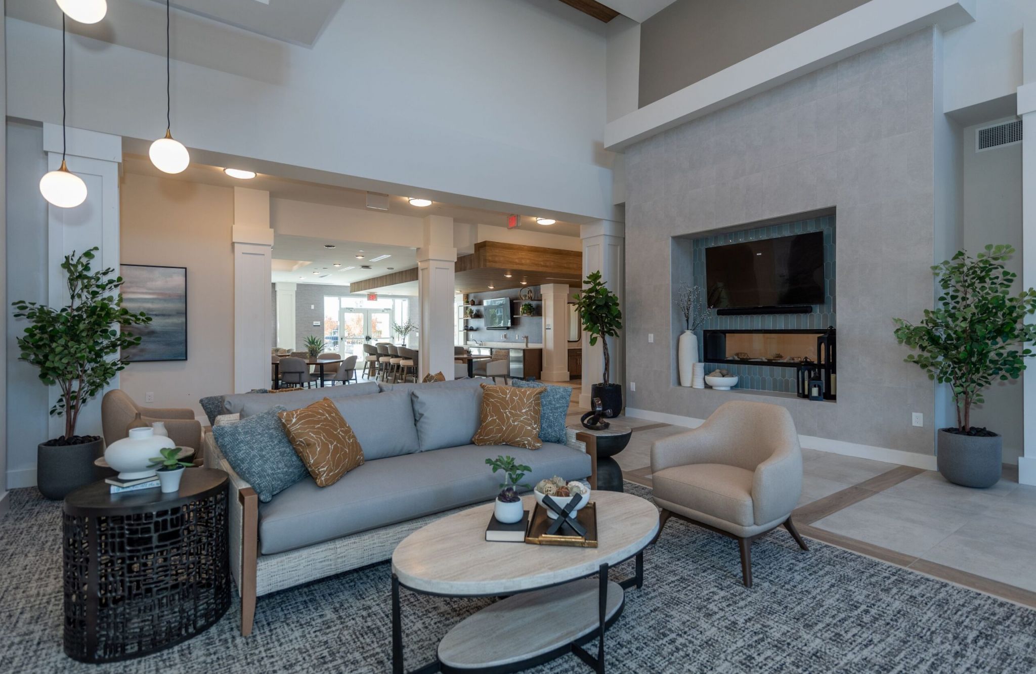 Modern living room on a hill with cozy furniture, a large rug, and a wall-mounted TV above a fireplace.