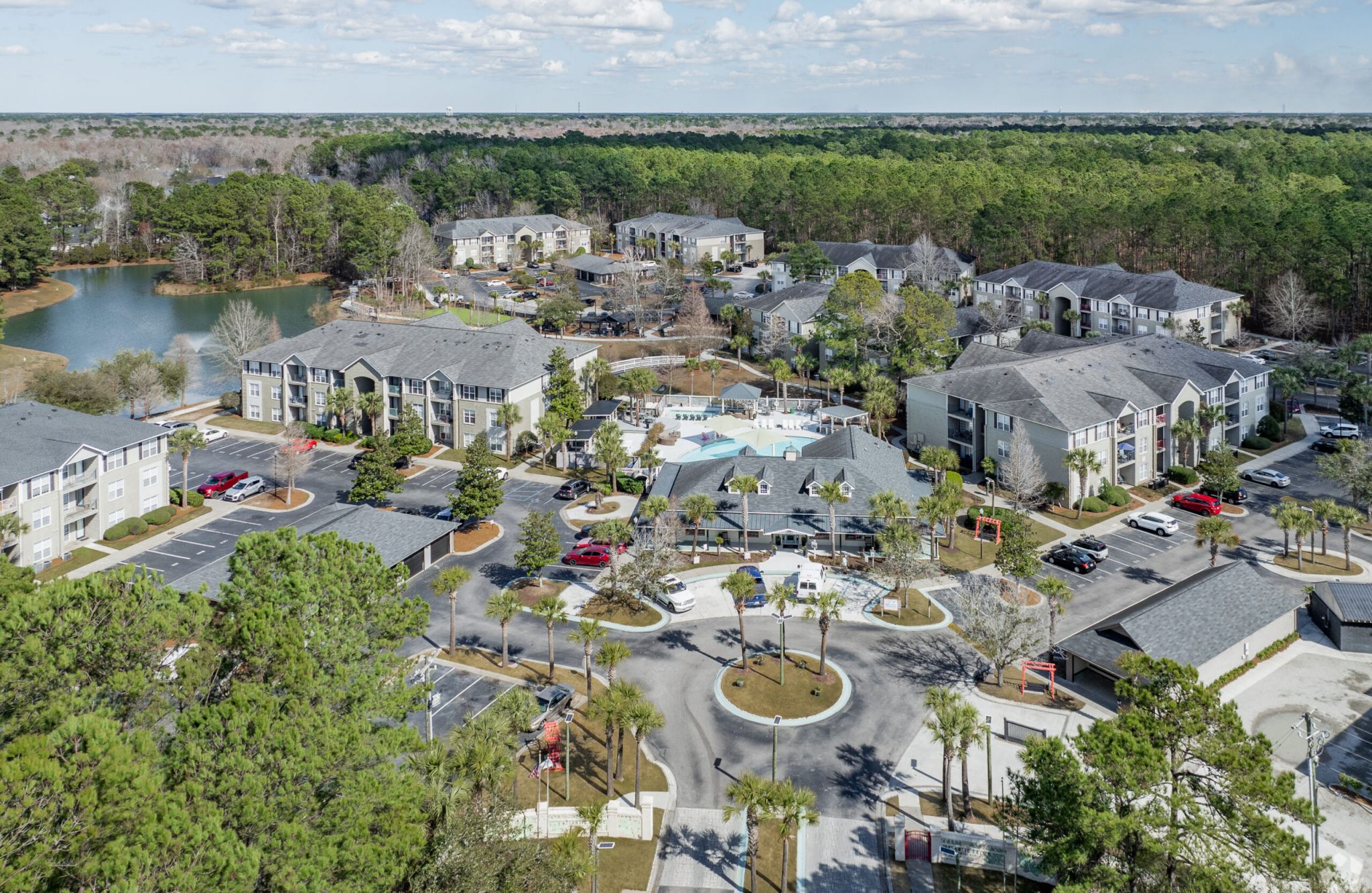 Aerial view of Atlantic Palms, a suburban apartment complex with parking lots, pool area, and surrounding trees.