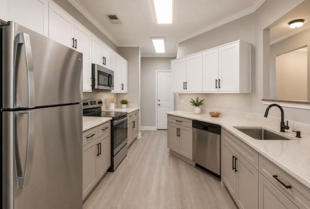 Modern kitchen with white cabinets, island with barstools, stainless steel appliances, and wooden flooring.