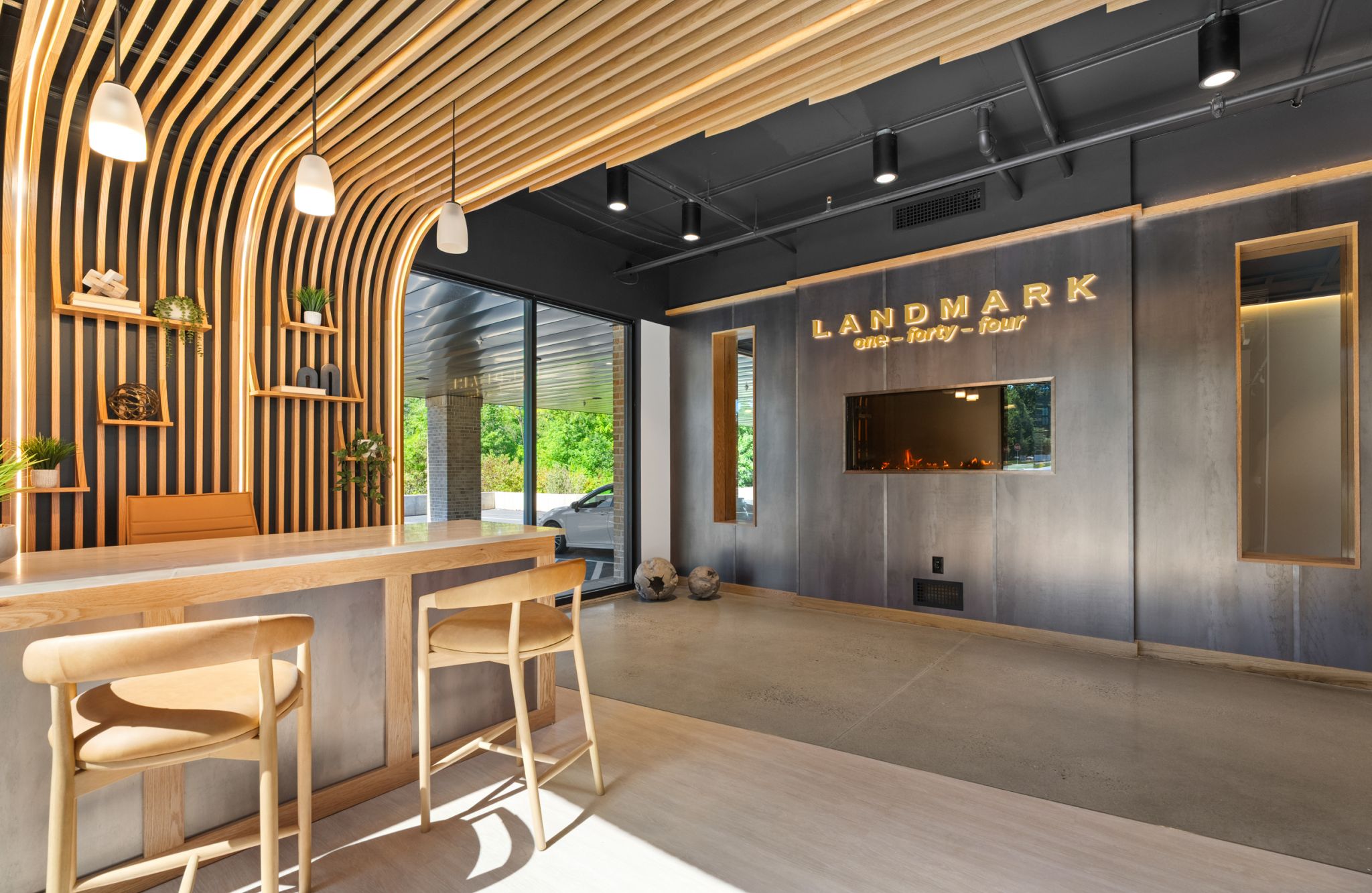 Modern office lobby at Landmark at Dublin with wooden accents, barstools, illuminated sign, and large windows flooding the space with light.