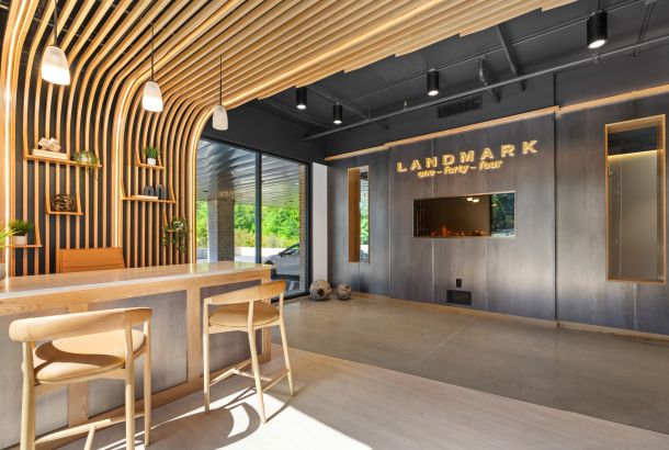 Modern office lobby at Landmark at Dublin with wooden accents, barstools, illuminated sign, and large windows flooding the space with light.