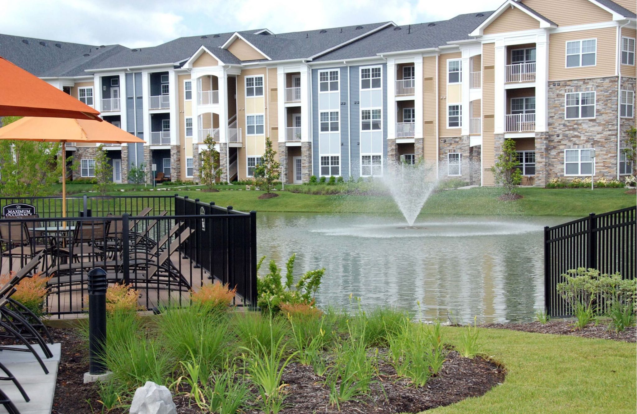 The Cascades: modern apartment buildings with a pond and fountain, surrounded by lush gardens and inviting outdoor seating areas.