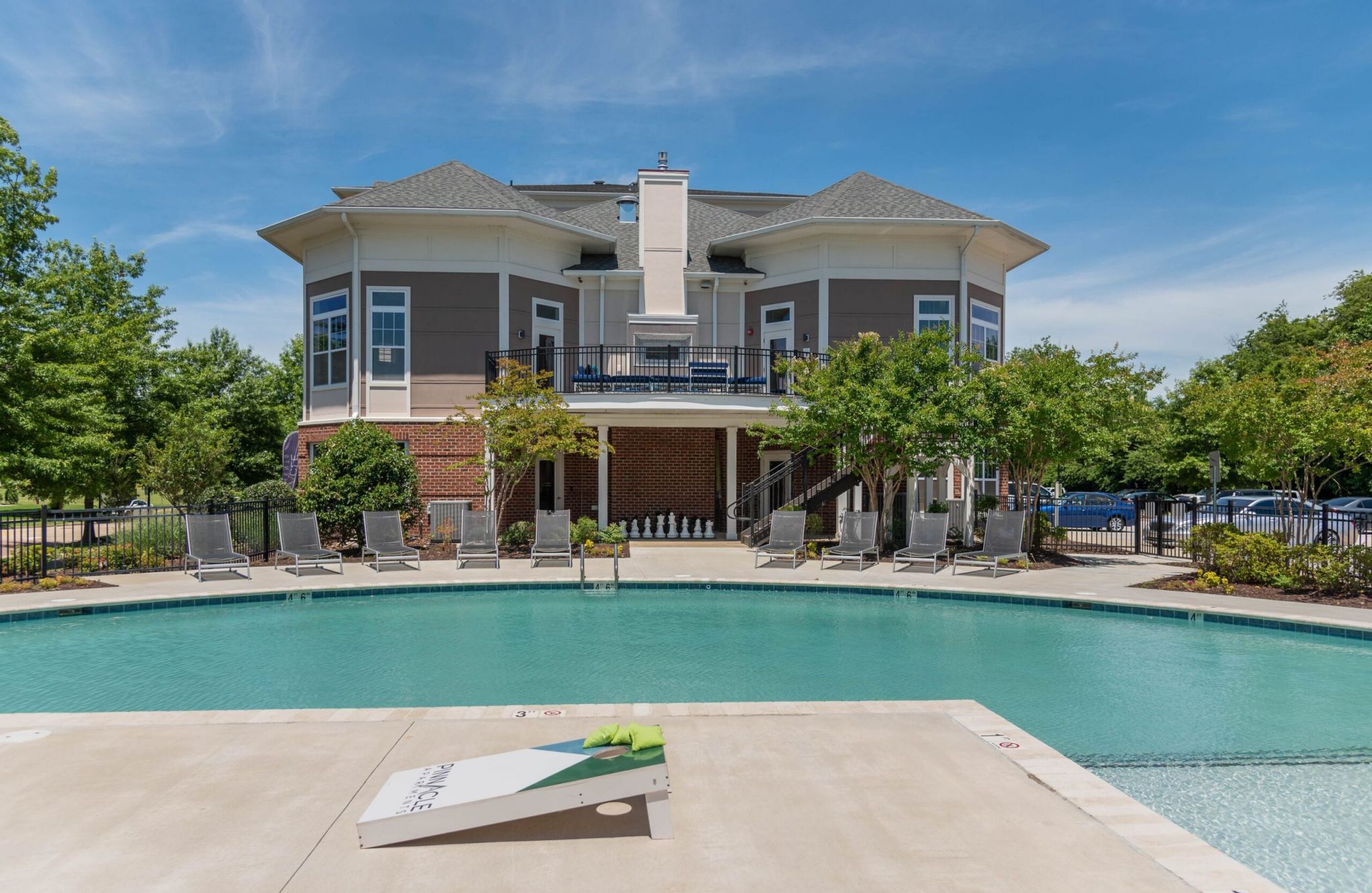 A modern building with a pool and sun loungers in front, under a clear blue sky.