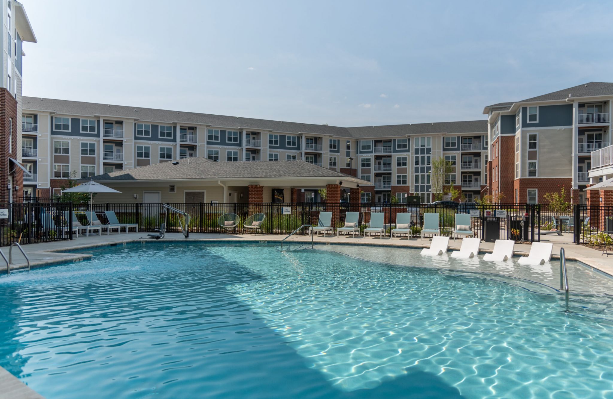 Attain Towne Centre apartment complex with a large swimming pool, lounge chairs, and blue sky in the background offers an ideal place to attain relaxation.