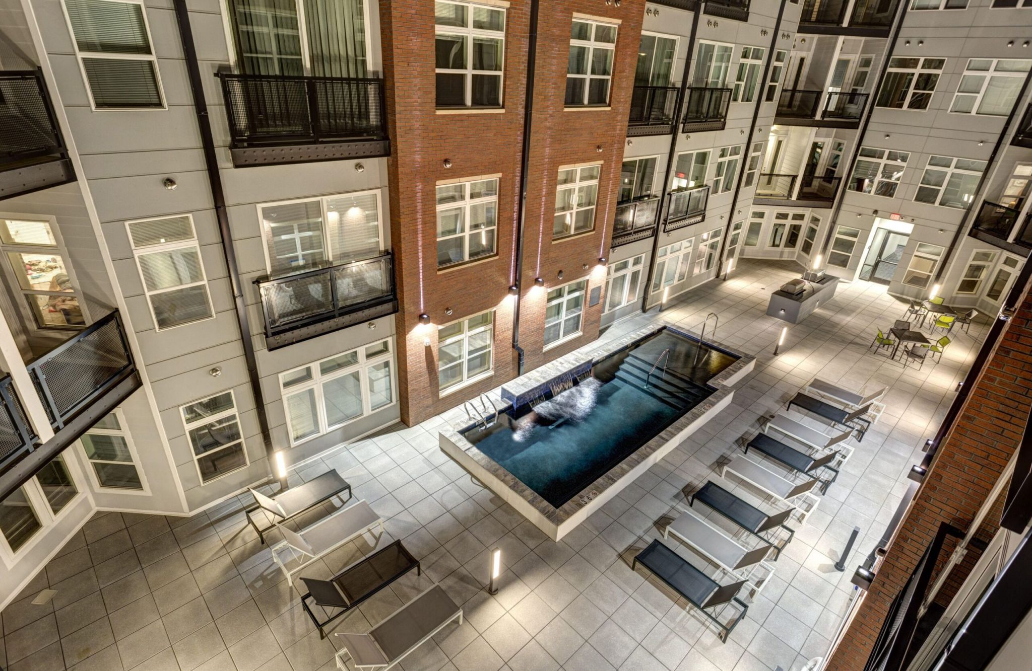 Modern apartment courtyard at Downtown East with a central pool, lounge chairs, and surrounding brick and white facade buildings.