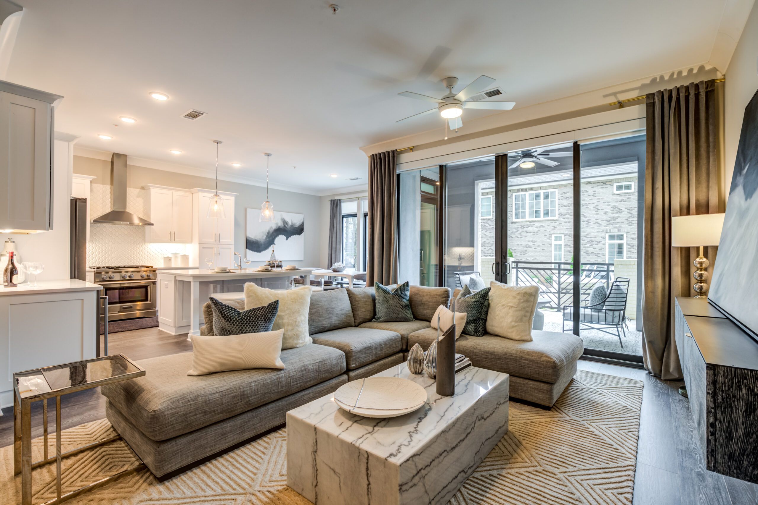 Modern living room at Draper Place with a large sectional sofa, marble coffee table, and glass doors leading to a balcony.