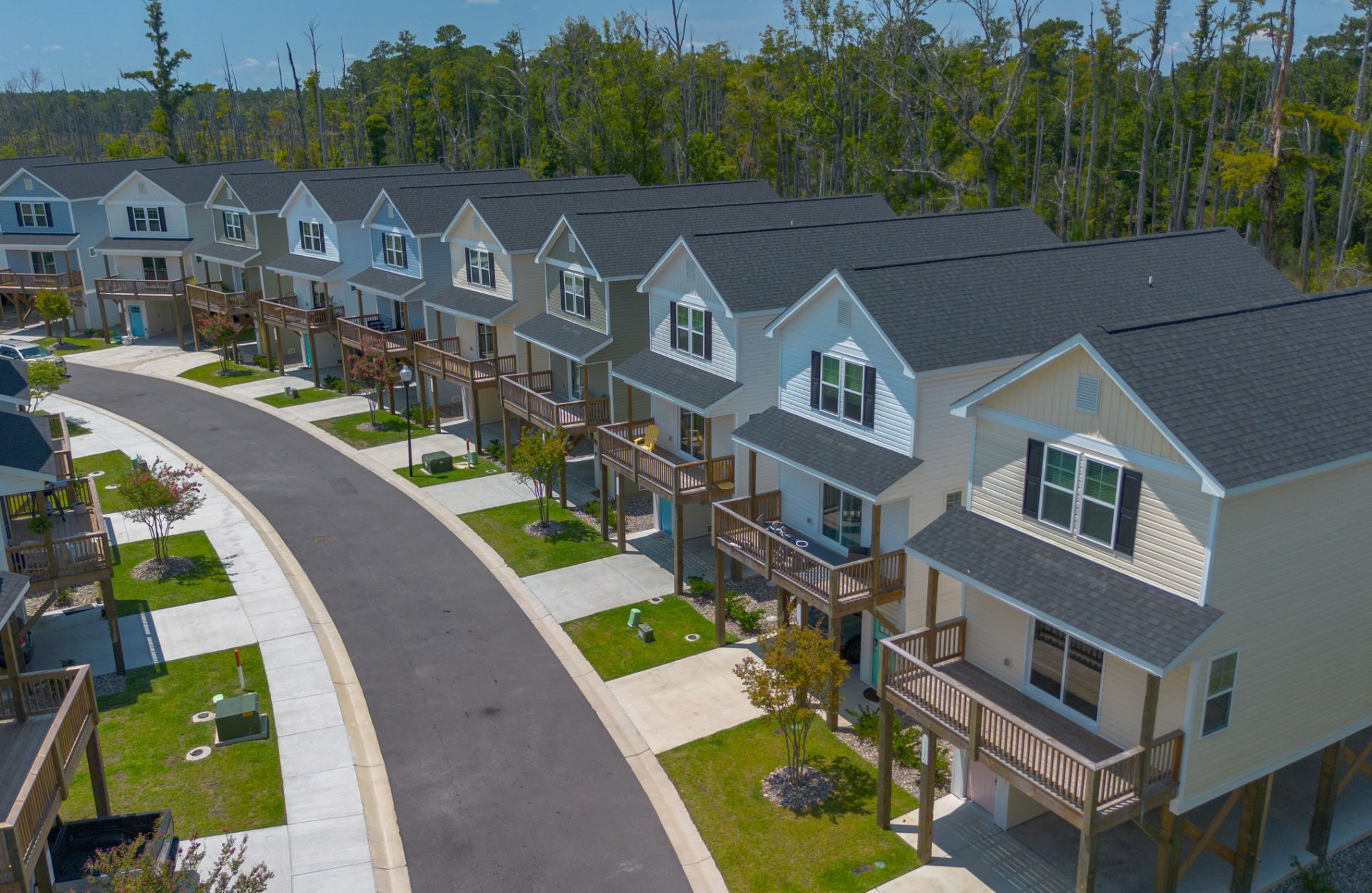 A row of identical two-story houses with front porches lines Overlook Drive, curving gently along the edge of Jackeys Creek.