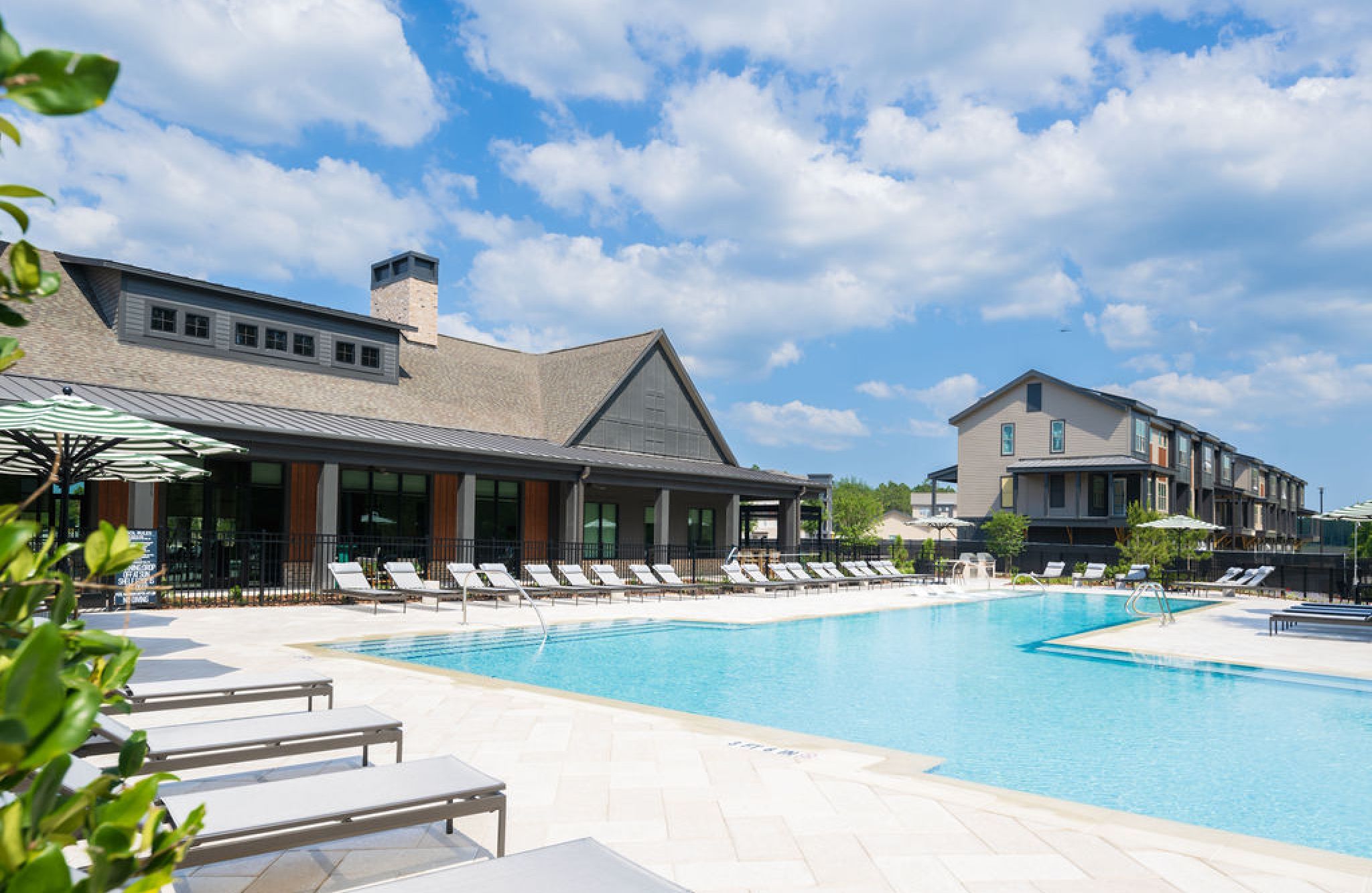 Seven Pines' outdoor swimming pool offers lounge chairs, a clubhouse, and apartments under a partly cloudy sky.