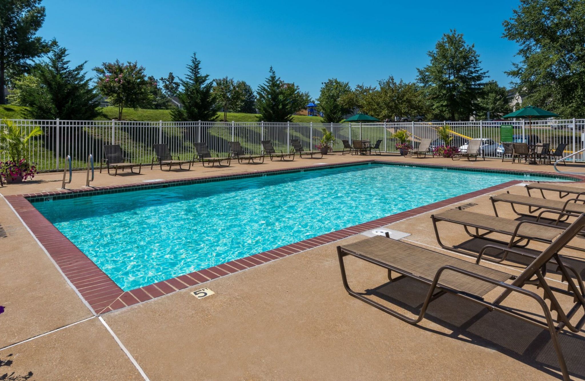 Outdoor swimming pool with lounge chairs and umbrellas on a sunny day.