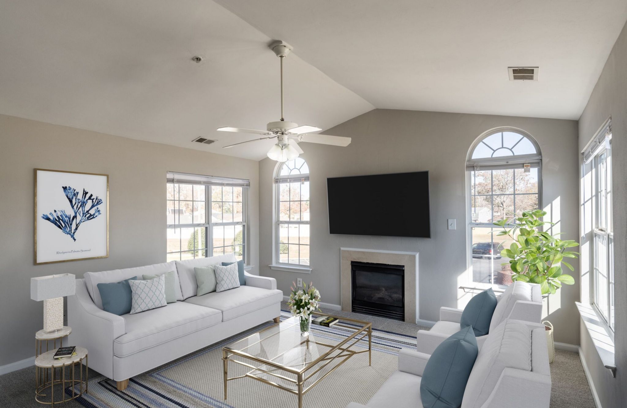 Bright living room with white sofas, a glass coffee table, Magnolia Run wall art, and a large window view.