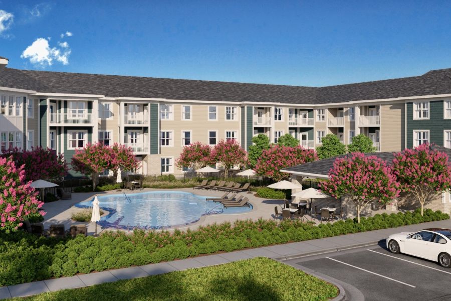 An apartment complex at Chics Beach, featuring a pool, pink-flowered trees, and a parking lot with a white car.