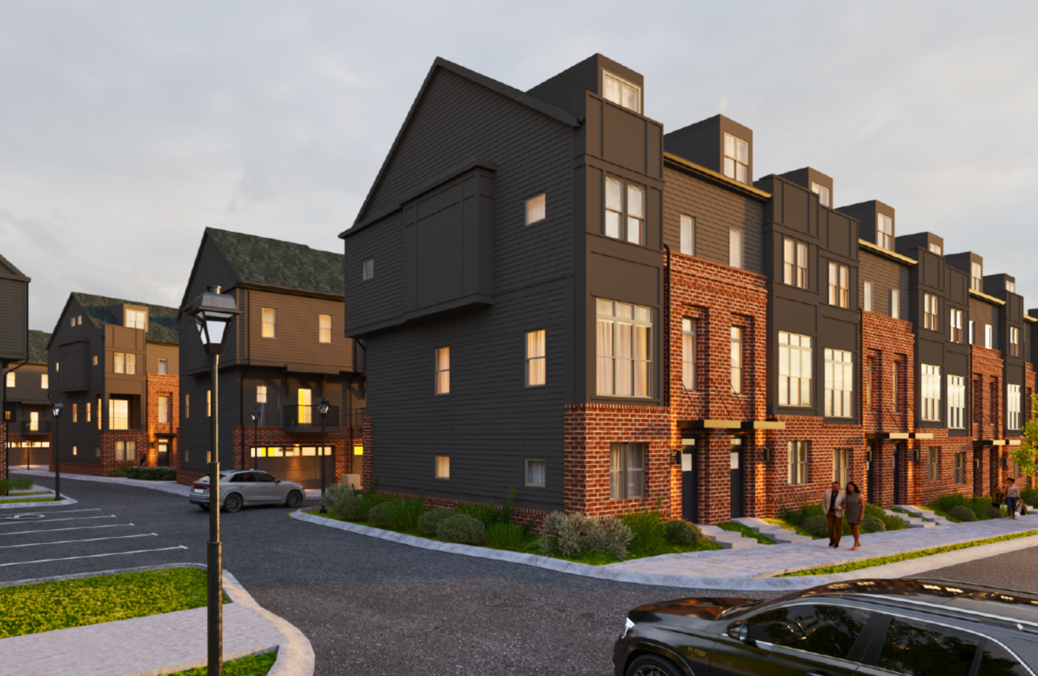 Modern townhouses at Two West End feature brick, dark siding, landscaped streets, parked cars, and locals strolling under a glowing streetlamp.