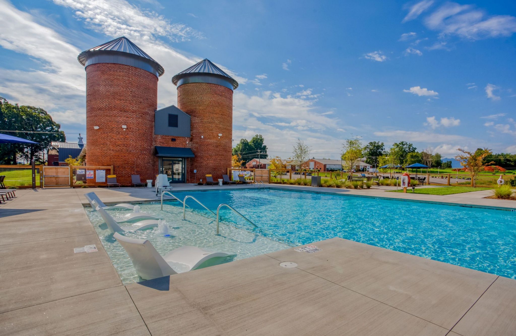 Murphy's Farm features an outdoor pool with loungers, set against the backdrop of two brick silos under a blue sky.