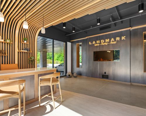 Modern office lobby at Landmark at Dublin with wooden accents, barstools, illuminated sign, and large windows flooding the space with light.
