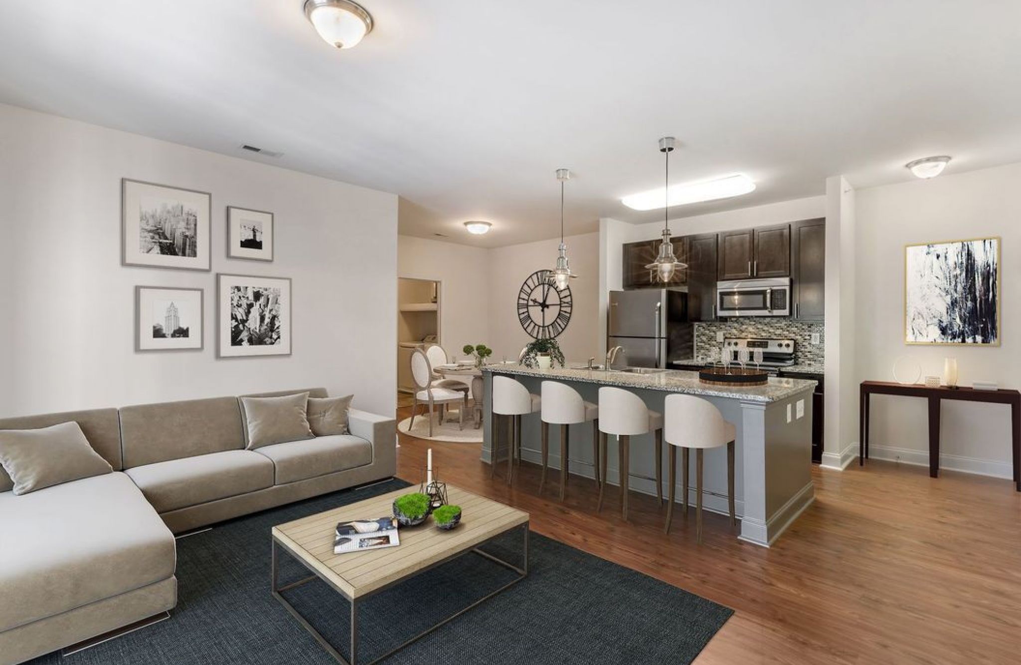 Modern open-concept living room and kitchen at Crest Gateway with a beige sectional sofa, bar stools, and dining area.
