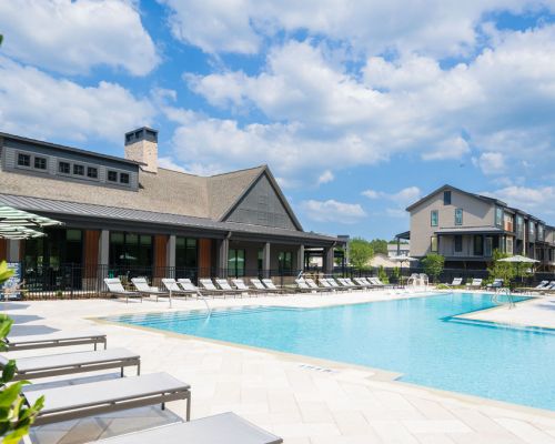 Seven Pines' outdoor swimming pool offers lounge chairs, a clubhouse, and apartments under a partly cloudy sky.