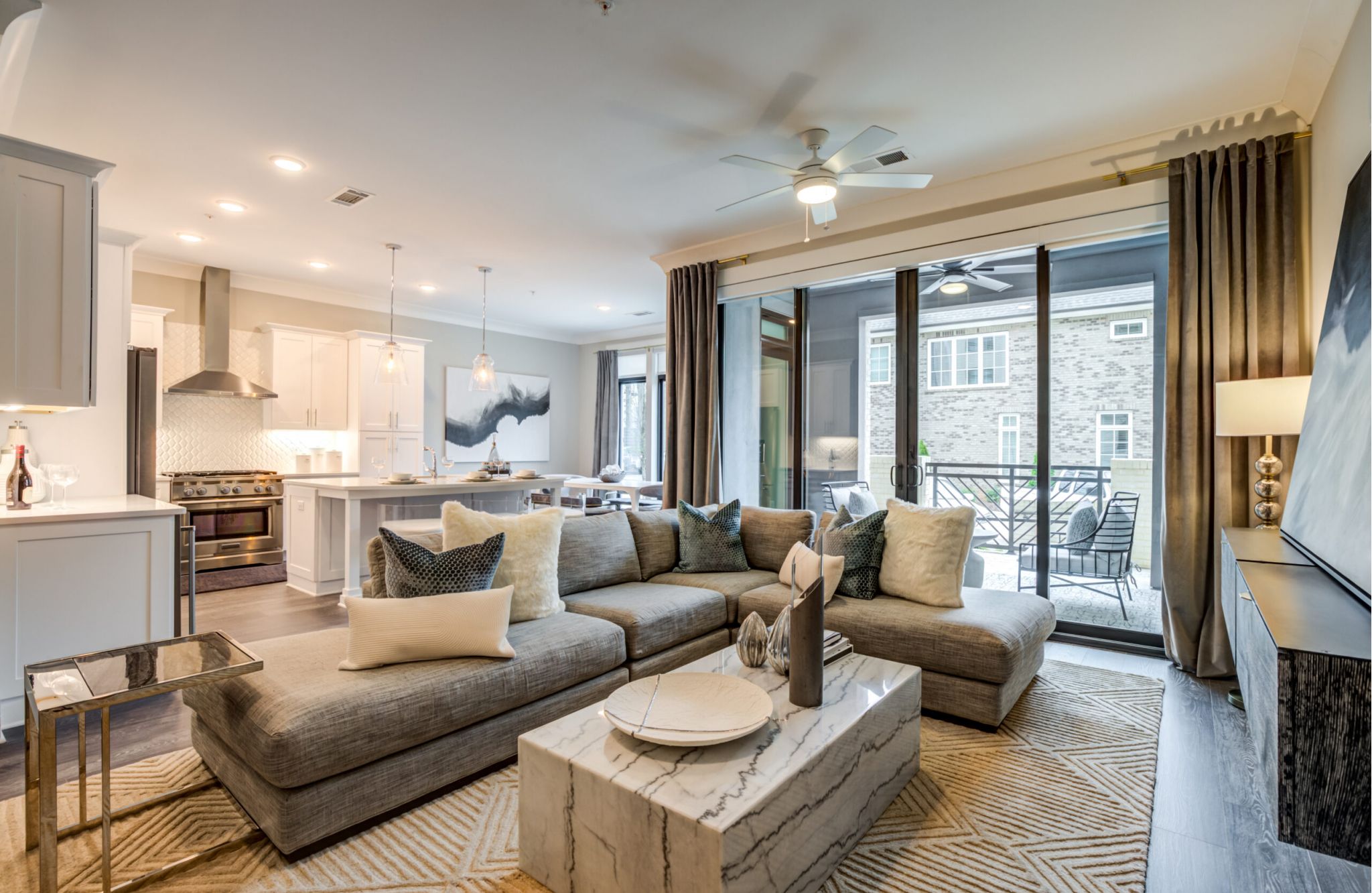 Modern living room at Draper Place with a large sectional sofa, marble coffee table, and glass doors leading to a balcony.