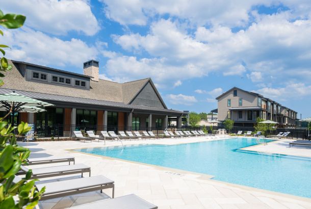 Seven Pines' outdoor swimming pool offers lounge chairs, a clubhouse, and apartments under a partly cloudy sky.