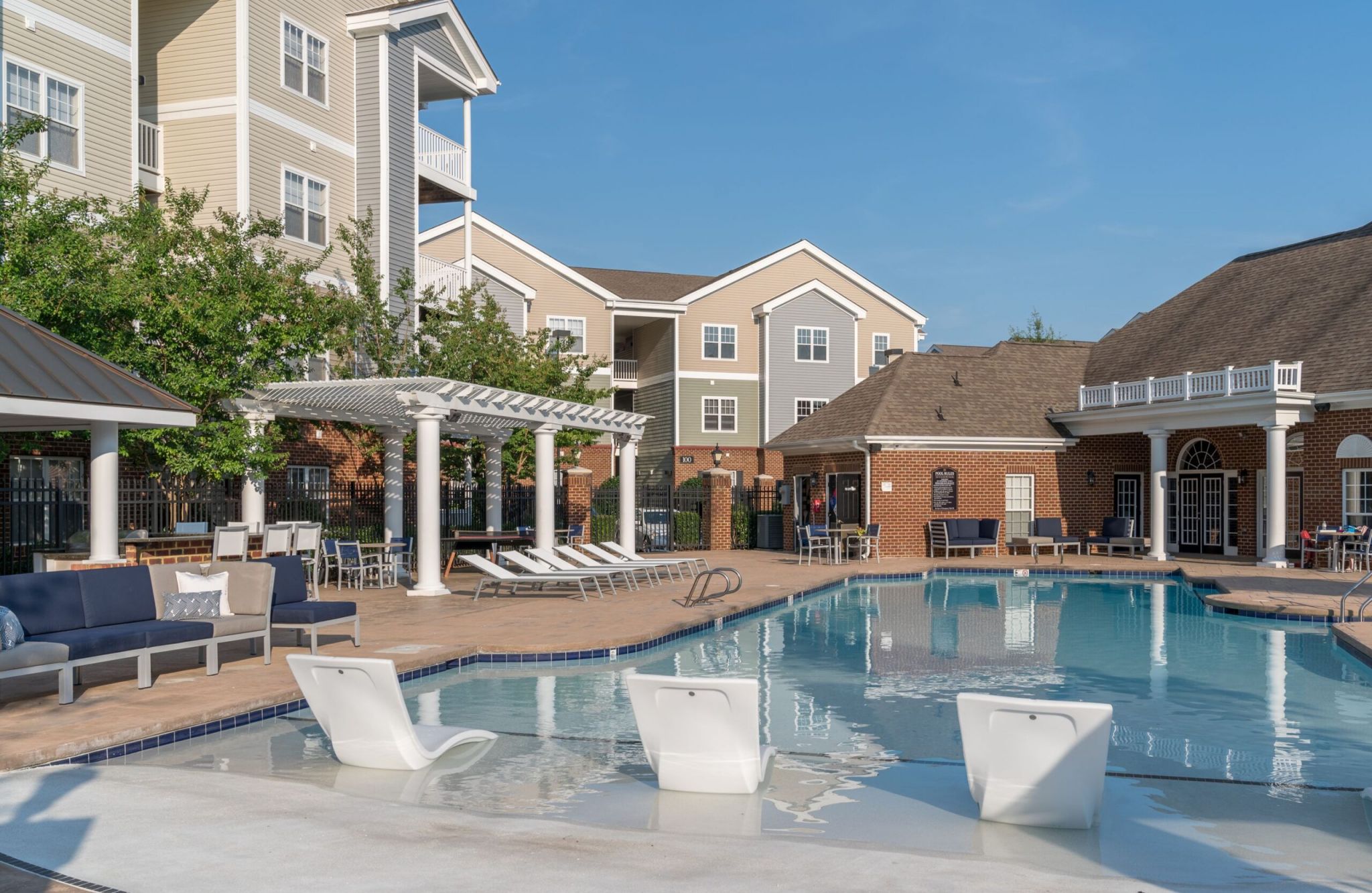 Meridian Parkside’s pool area features lounge chairs, a pergola, and scenic buildings under a clear blue sky.